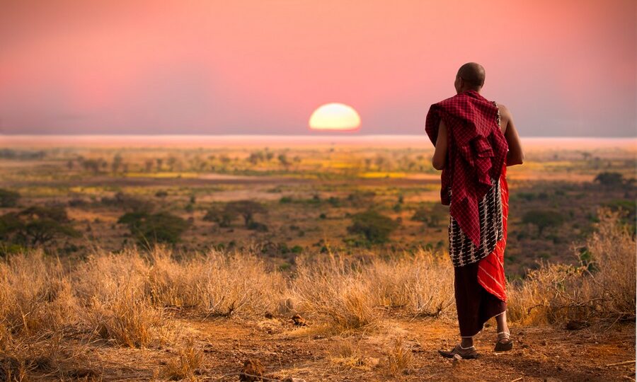 Un Masai osserva il tramonto sulla pianura del Serengeti nell'area della Tanzania