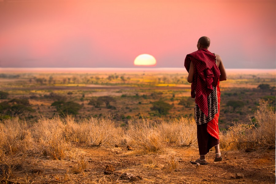 Un Masai osserva il tramonto sulla pianura del Serengeti nell'area della Tanzania